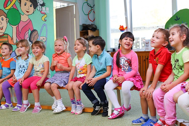 Kinder, die im Halbkreis auf einer Bank sitzen und lachen_neu