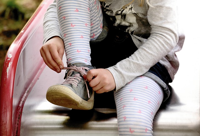 Pixabay-Foto auf dem ein Mädchen auf einer Rutsche sitzt und sich den Schuh bindet