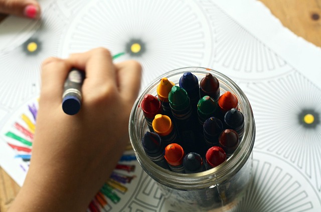 Pixabay-Foto auf dem ein Glas mit Stiften und eine malende Kinderhand zu sehen ist